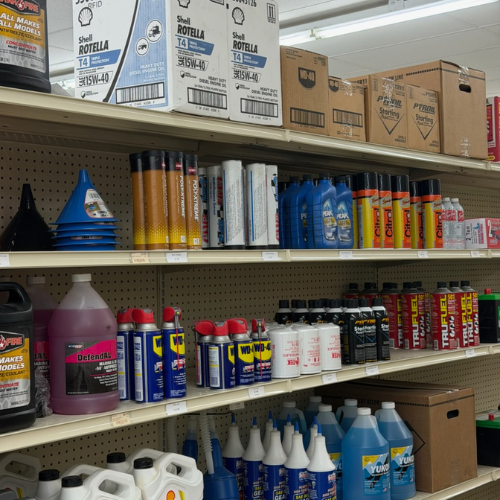 Store shelves filled with automotive supplies, including oil, funnels, and cleaners. The organized display features vibrant containers and boxes.